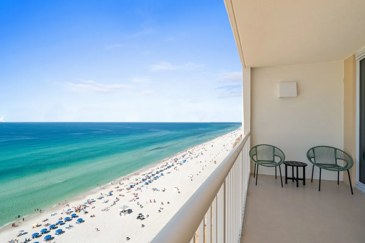 An exterior view from a balcony, highlighting beach chairs lined up facing a panoramic ocean view beyond a railing. The scene evokes a sense of calm and leisure, perfect for sunbathing, relaxing, or simply enjoying the scenic beauty.