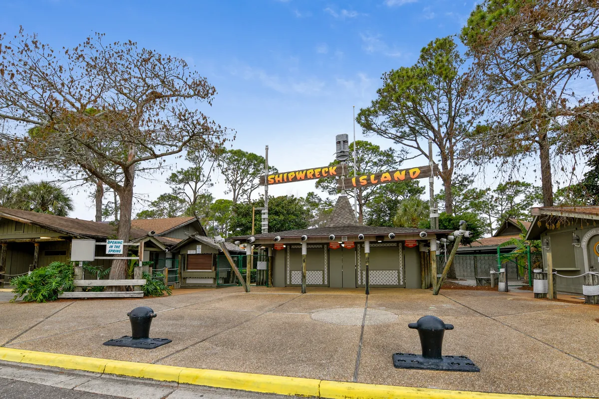 The entrance to Shipwreck Island Water Park, marked by its signature sign, rustic gates, and cabins nestled among large trees. While the park is currently closed, the image evokes anticipation and excitement for the adventures that await inside.